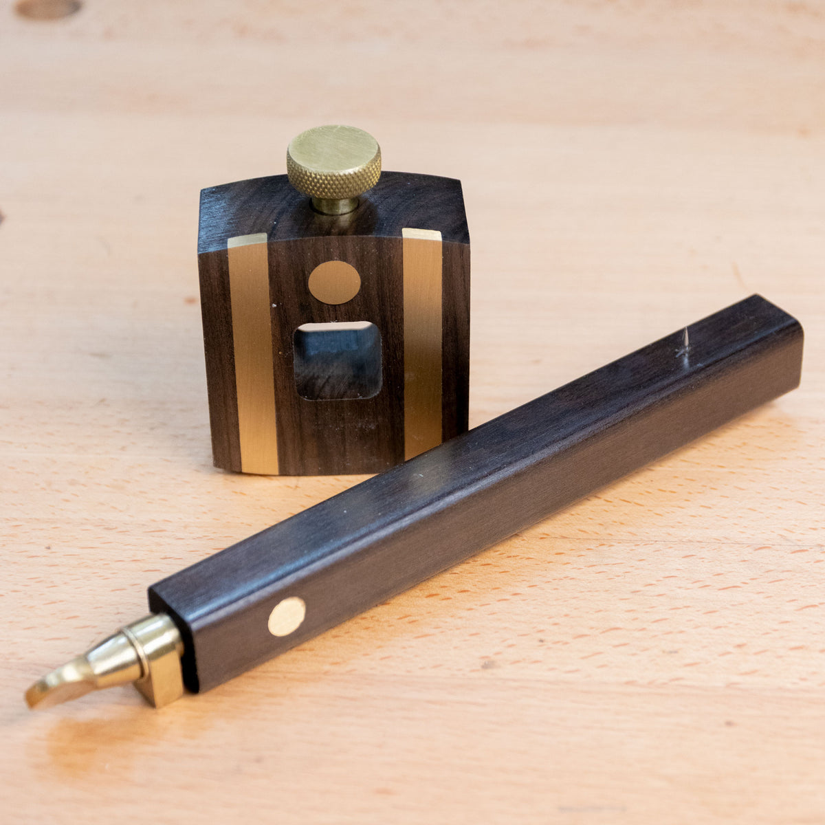 Ebony marking gauge with brass accents on a woodworking bench