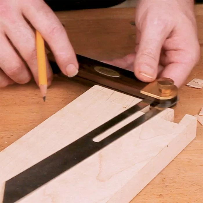 Woodworker using a bevel gauge and pencil to mark a precise angle on a wood board