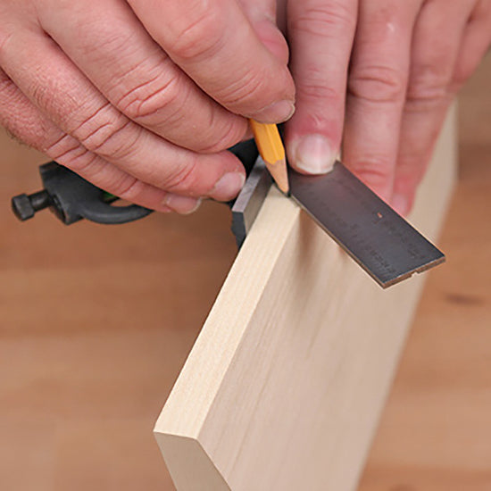 Woodworker marking a board with a combination square and pencil for precise woodworking