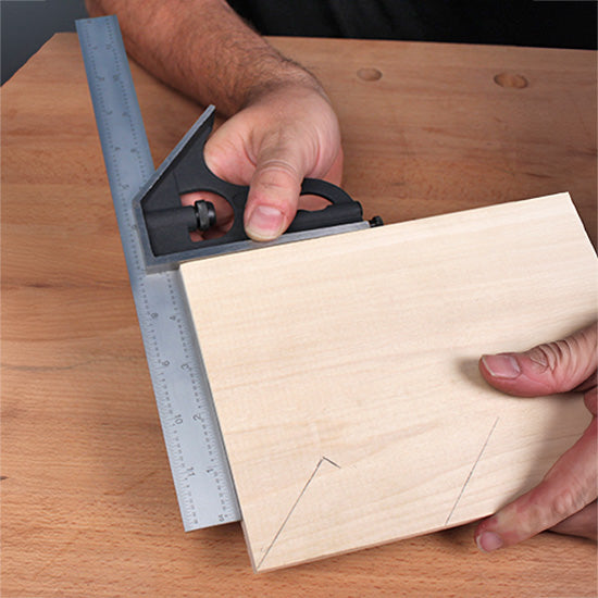 Person using a combination square to mark lines on a piece of wood for woodworking precision.