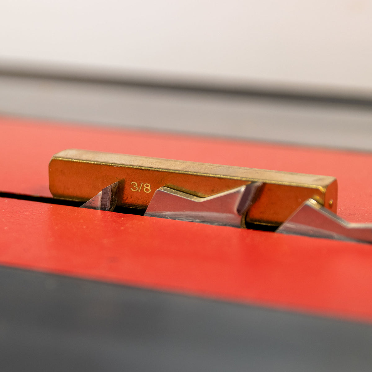 Brass setup bar measuring blade height on tablesaw for precise woodworking cuts.