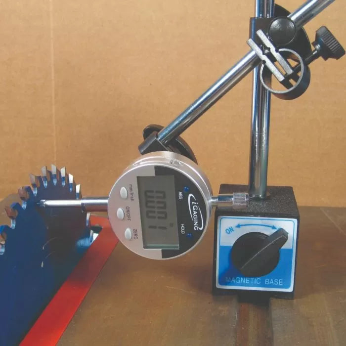 Digital indicator gauge with magnetic base measuring saw blade alignment on a woodworking table.