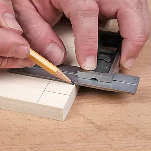 Woodworker marking precise dovetail layout on wood with a combination square and pencil.