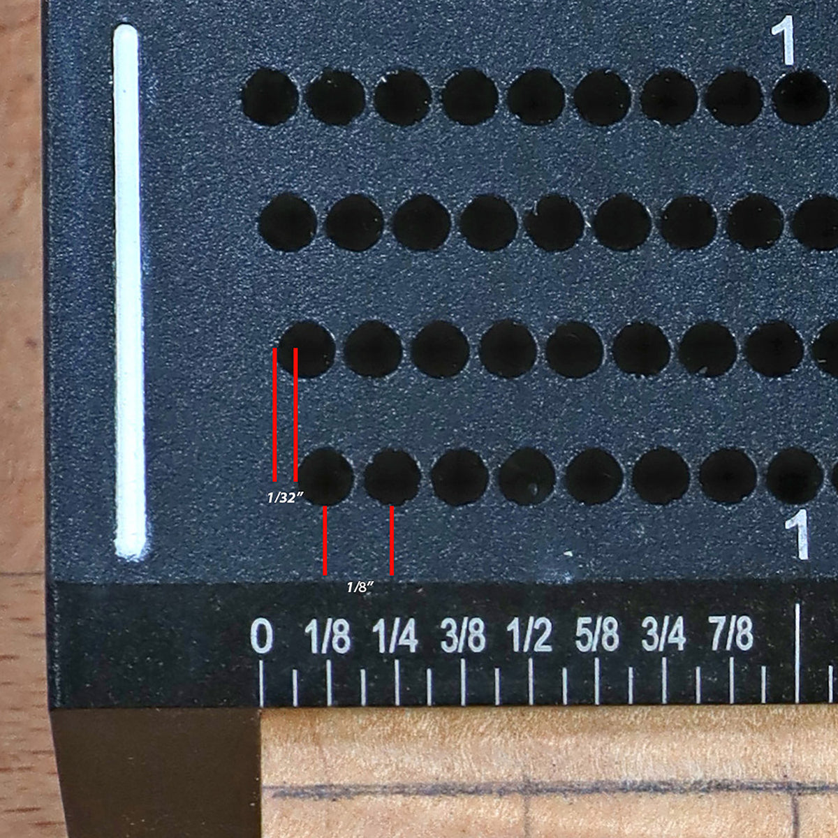 Close-up of woodworking jig with offset hole guide and inch measurements for precise drilling.