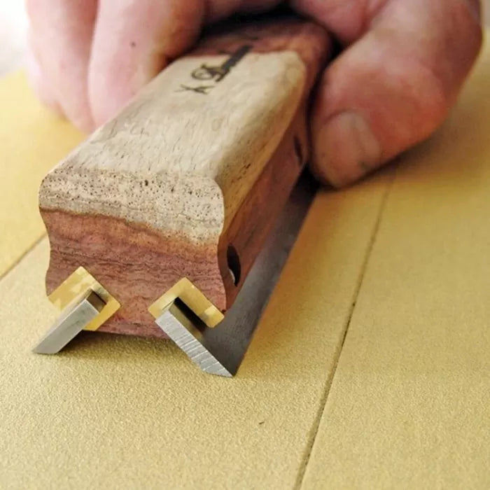 Woodworking marking gauge tool with dual blades, close-up on hand guiding on wood surface