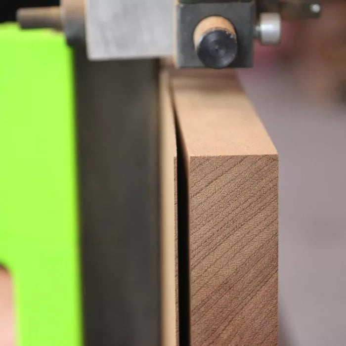 Close-up of a woodworking bandsaw fence and guide cutting a straight line on a wood board