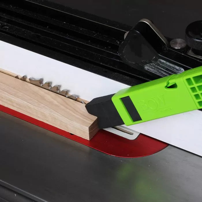 Push stick guiding wood on table saw blade for safe woodworking cut