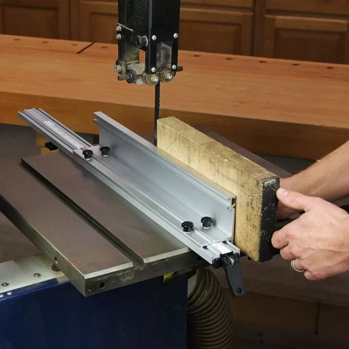 Band saw with aluminum fence cutting wood in woodworking shop setting