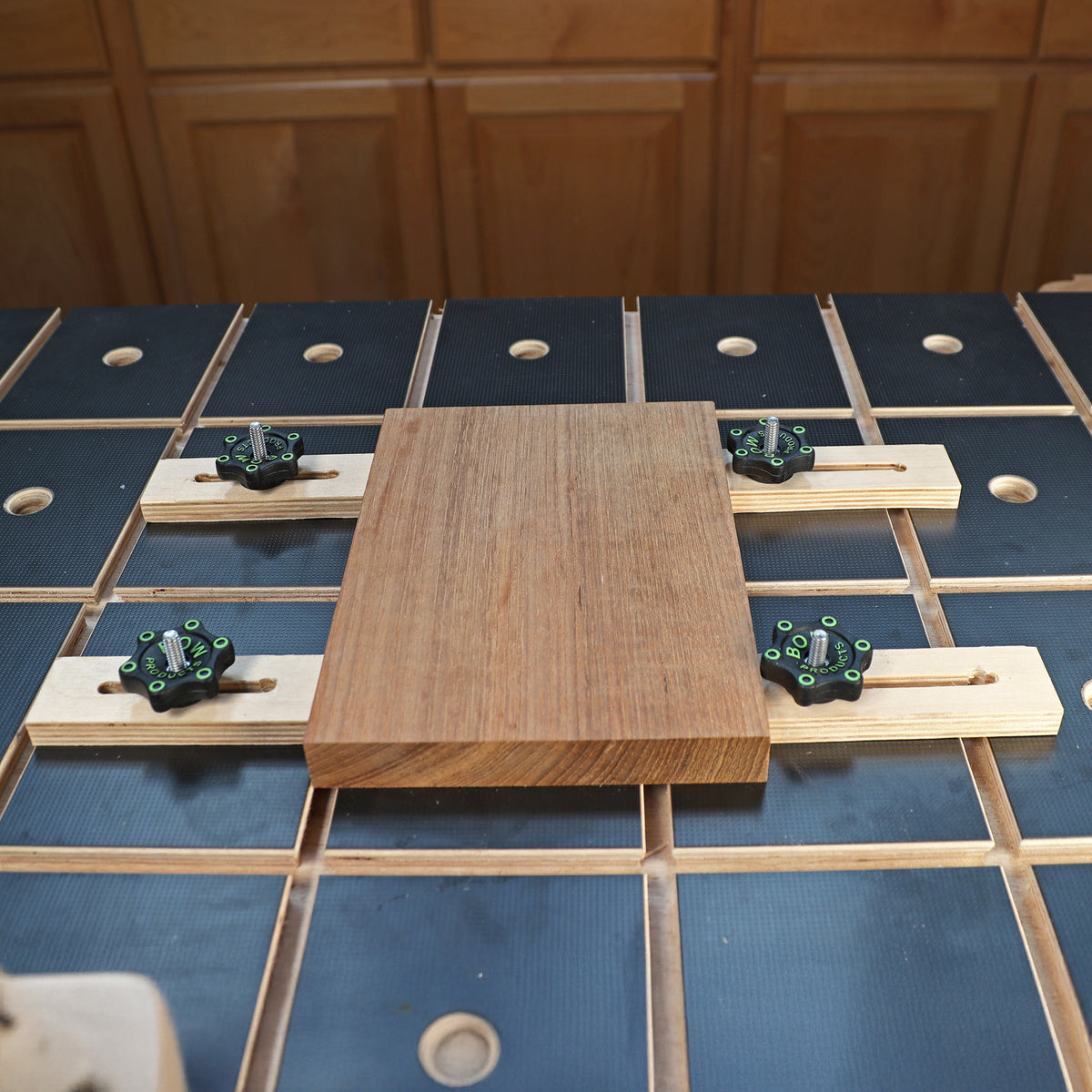Woodworking workbench with toggle clamp hold-downs securing a wood board