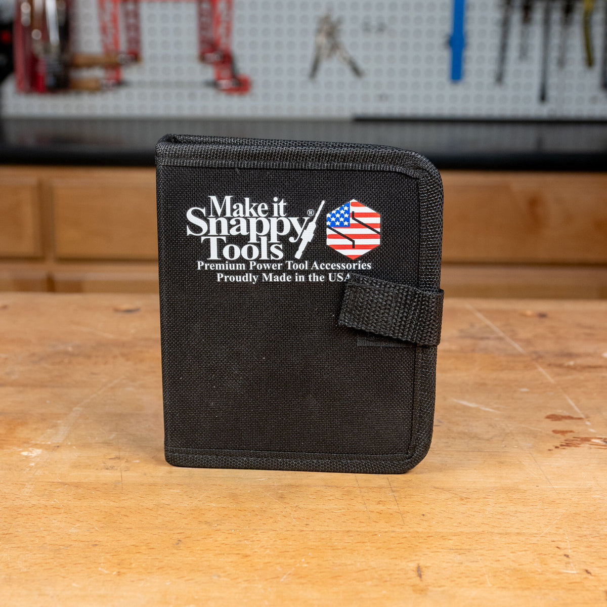 Black tool bit case labeled 'Make it Snappy Tools' on a woodworking bench in workshop setting