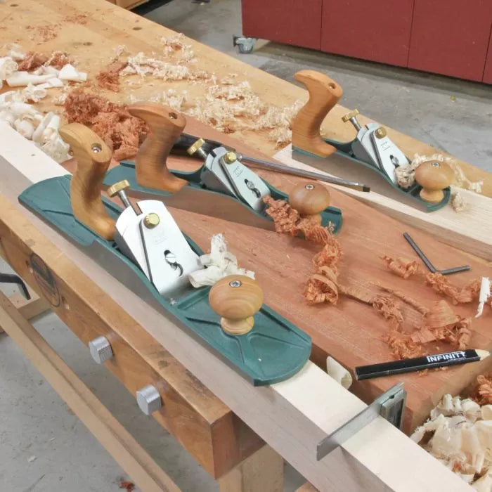 Woodworking hand planes and wood shavings on a workbench in a workshop setting
