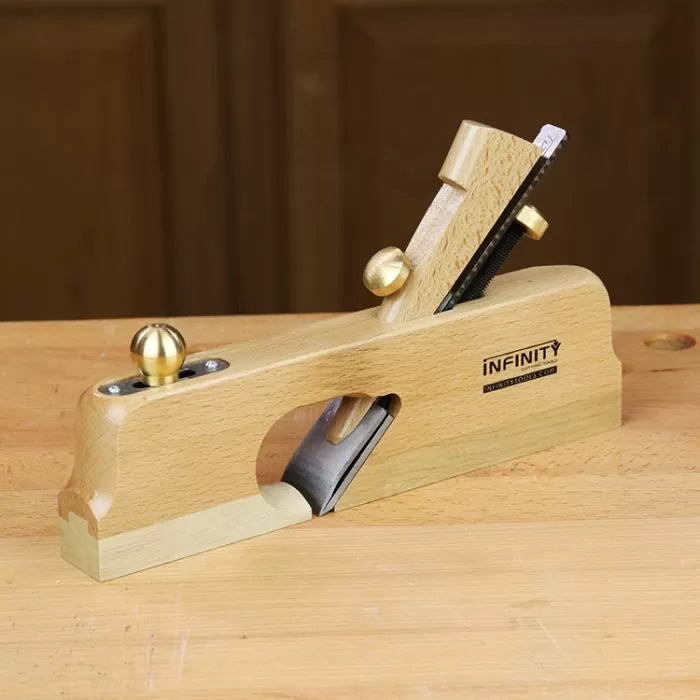 Wood jointer hand plane with brass fittings on a workbench for woodworking precision.