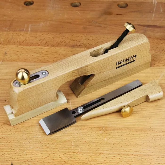 Wooden shoulder plane with brass hardware and removable blade on a workbench.