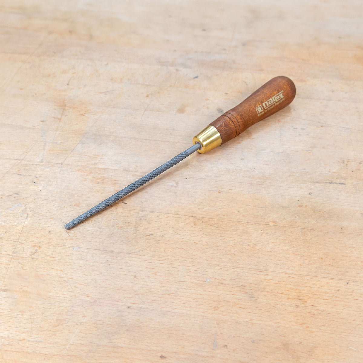 A round rasp sitting on a wooden bench.