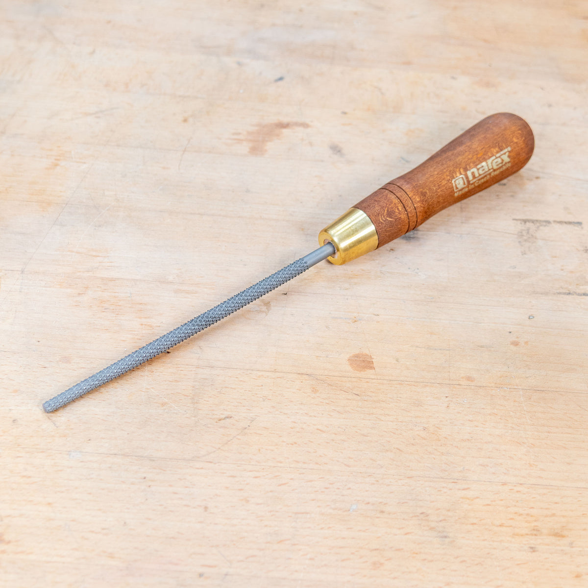 A round rasp sitting on a wooden bench.