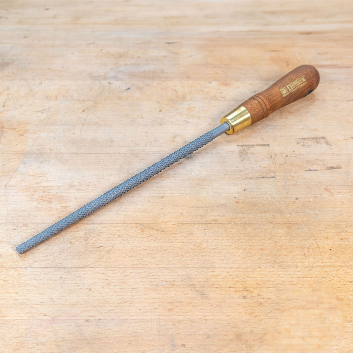 A round rasp sitting on a wooden bench.