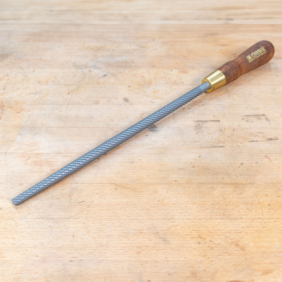 A round rasp sitting on a wooden bench.
