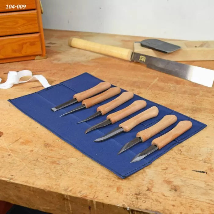 Wood carving knife set with wooden handles in blue tool roll on a workshop bench