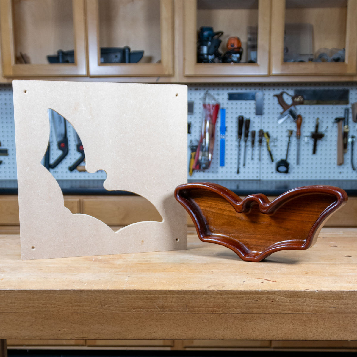 Bat-shaped woodworking tray with matching MDF template on a workshop bench