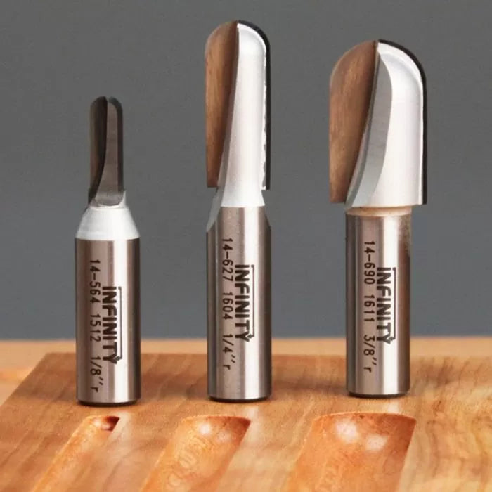 Three carbide woodworking router bits in different sizes on a wooden surface