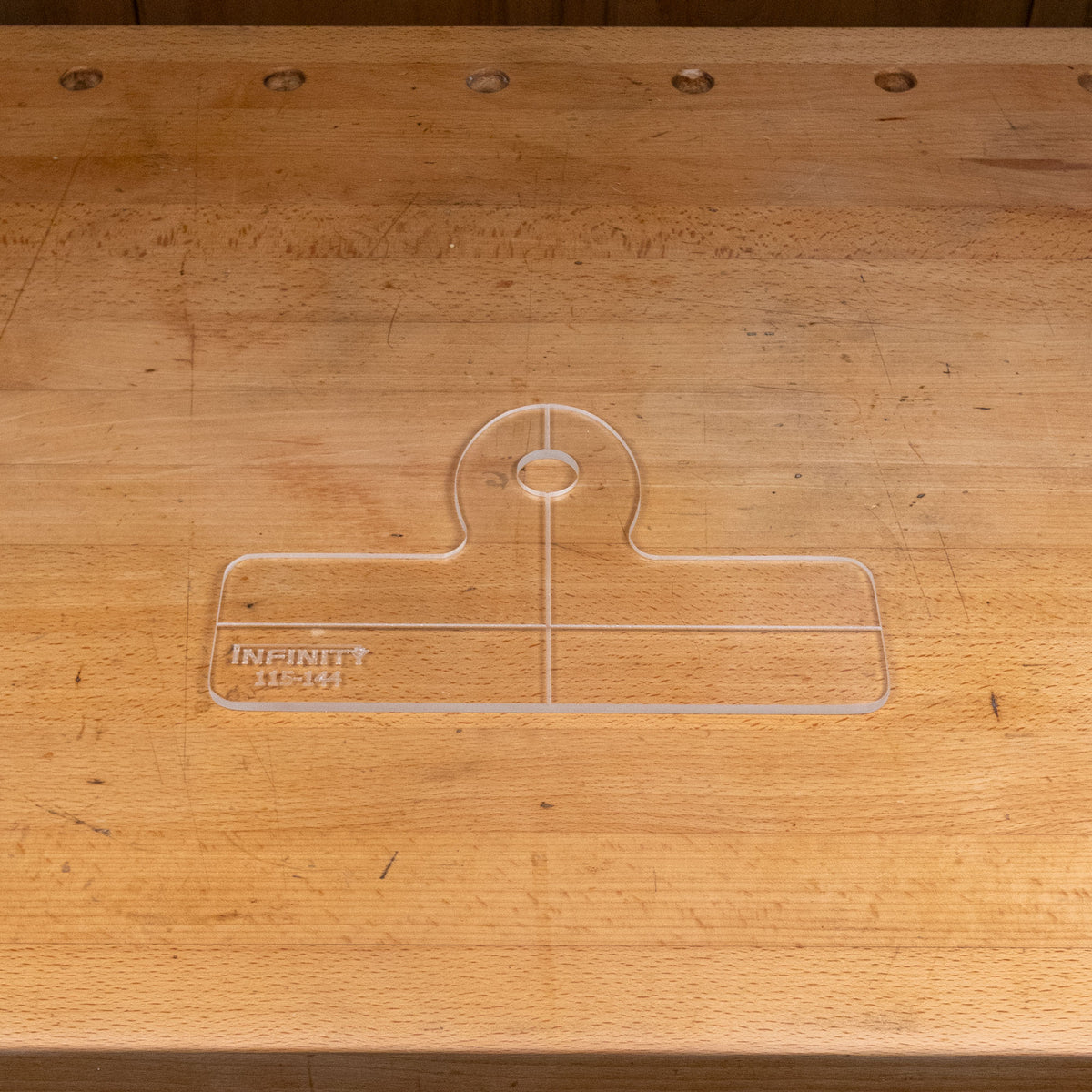 Clear acrylic handle template with engraved guidelines on a woodworking bench