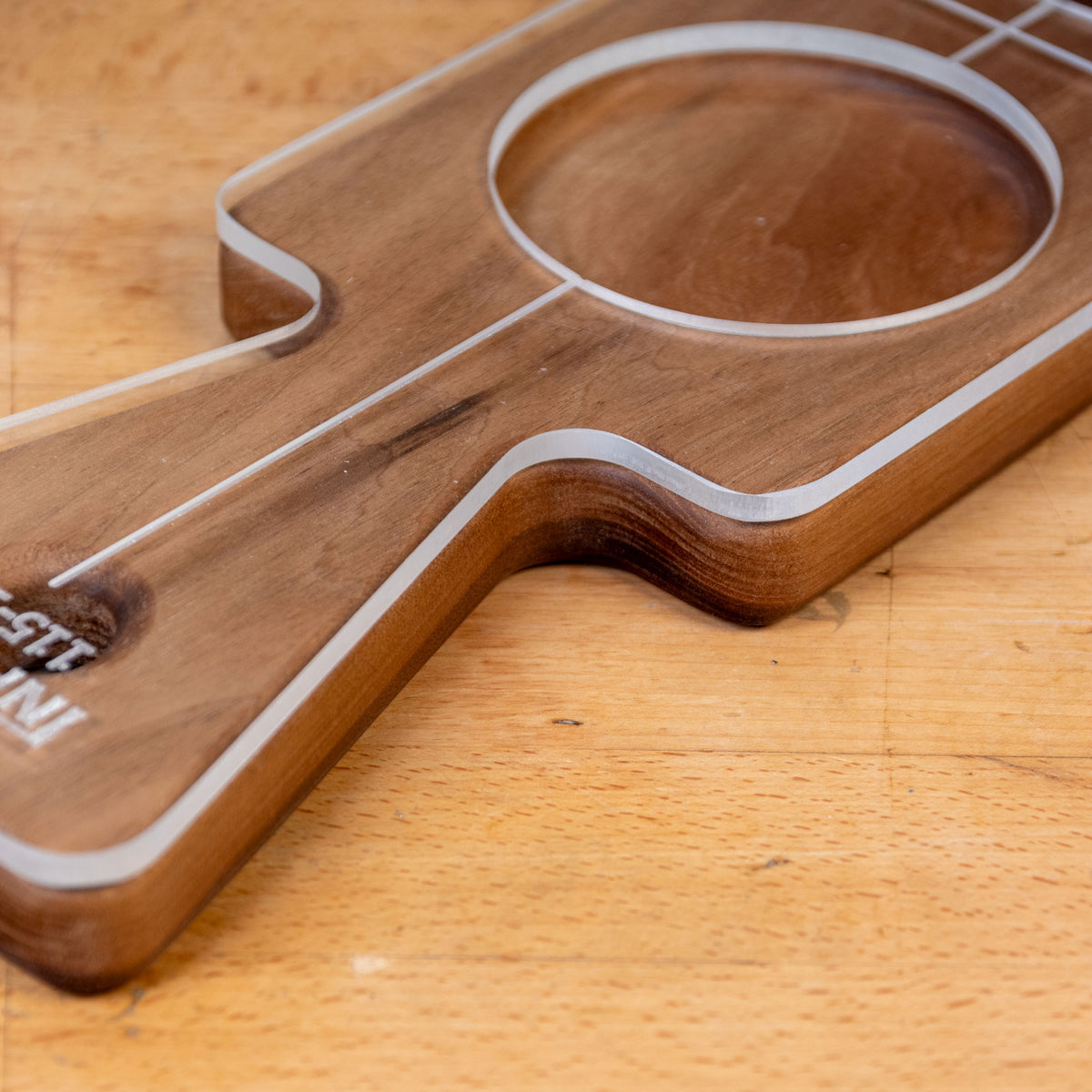 Acrylic router cutting board template with handle and circular cutout on a wooden surface