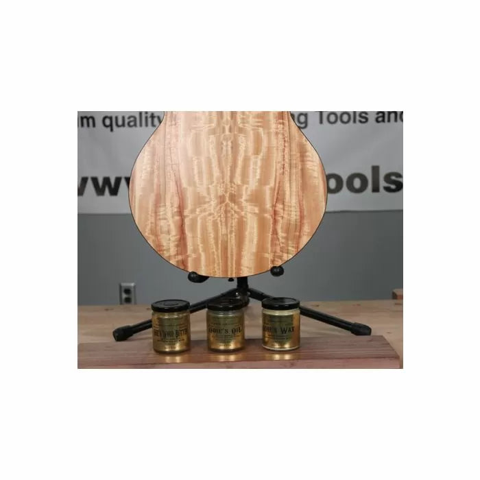 Glossy finished wood guitar body on stand with three wood finish jars on workbench