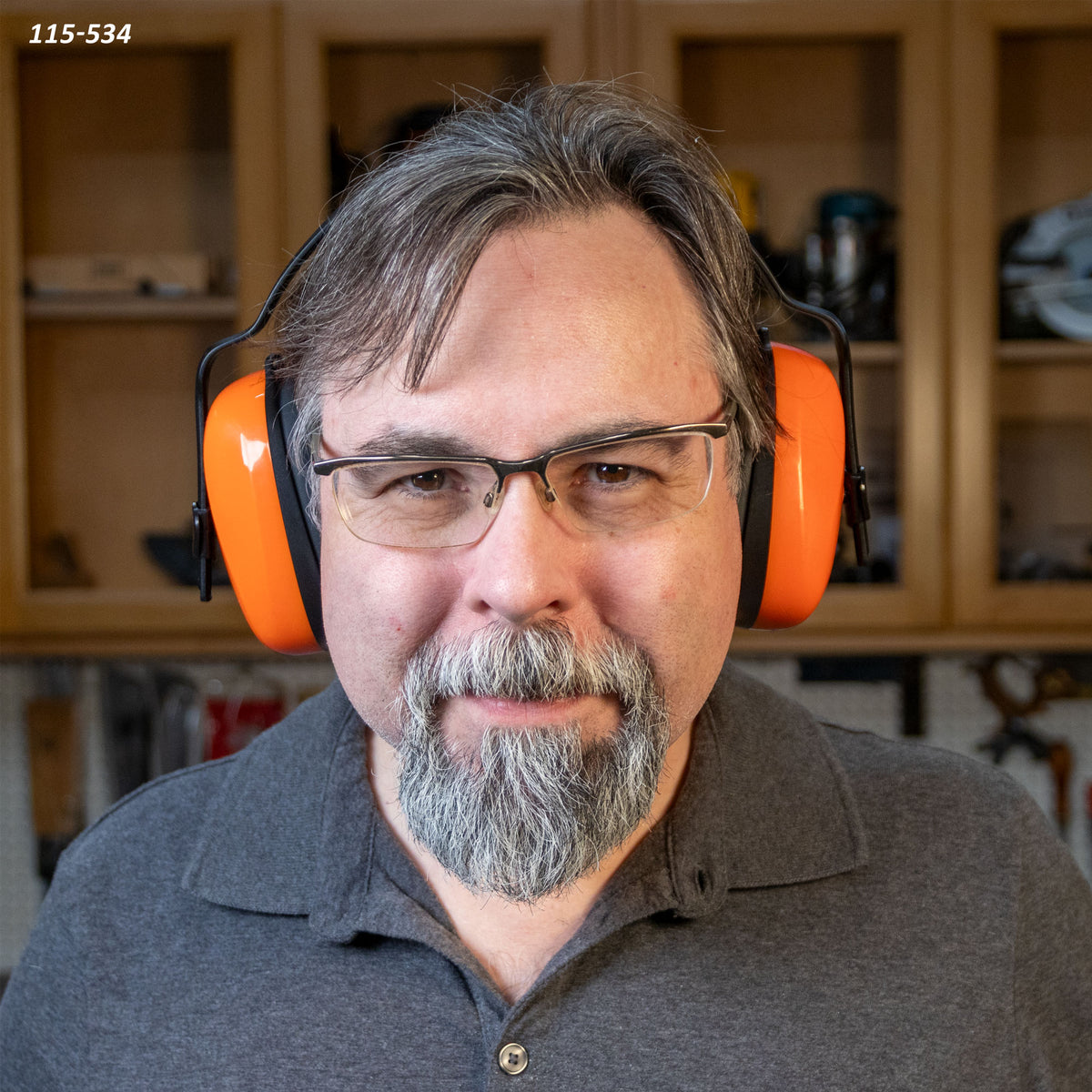 Man wearing orange NRR 24 earmuffs and safety glasses in a woodworking shop