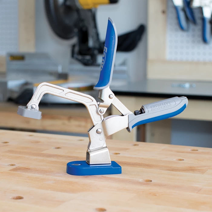 Woodworking bench clamp tool with blue handles on a workbench in a workshop setting