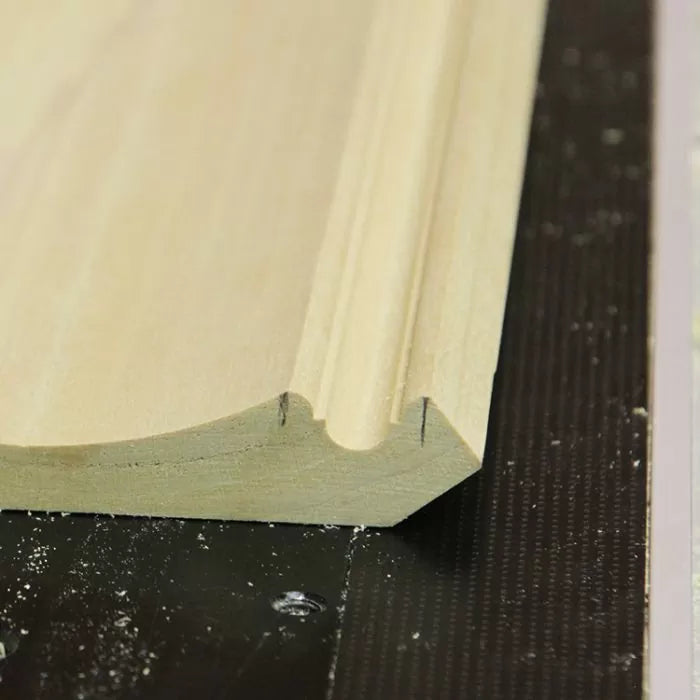 Close-up of decorative crown molding wood profile with detailed routed edge on workbench