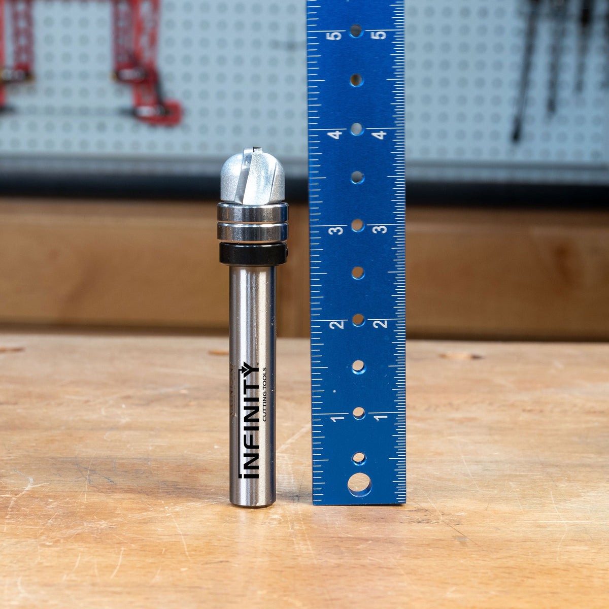 Bowl and tray router bit with bearing shown beside a blue ruler on a workbench