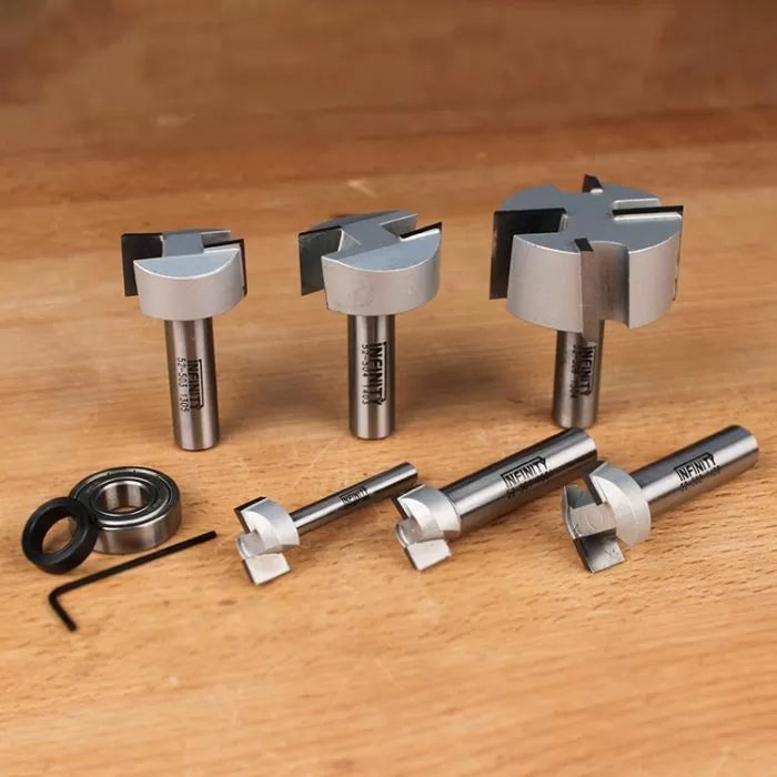 Set of precision woodworking router bits and bearings on wooden surface