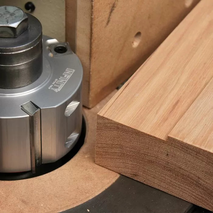 Woodworking router table cutter head trimming wooden board close-up