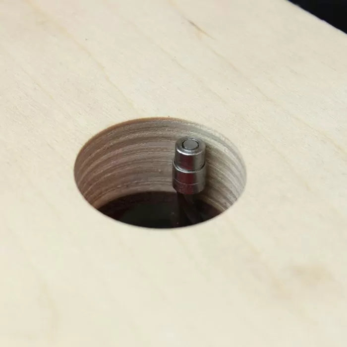 Close-up of a flush trim router bit cutting a circular hole in plywood.