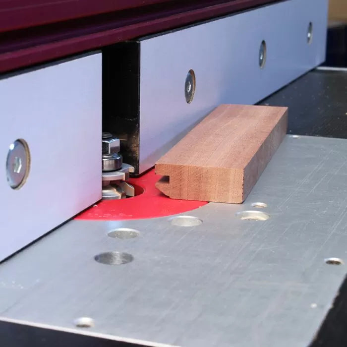 Woodworking router table setup with router bit cutting a wooden board for joinery