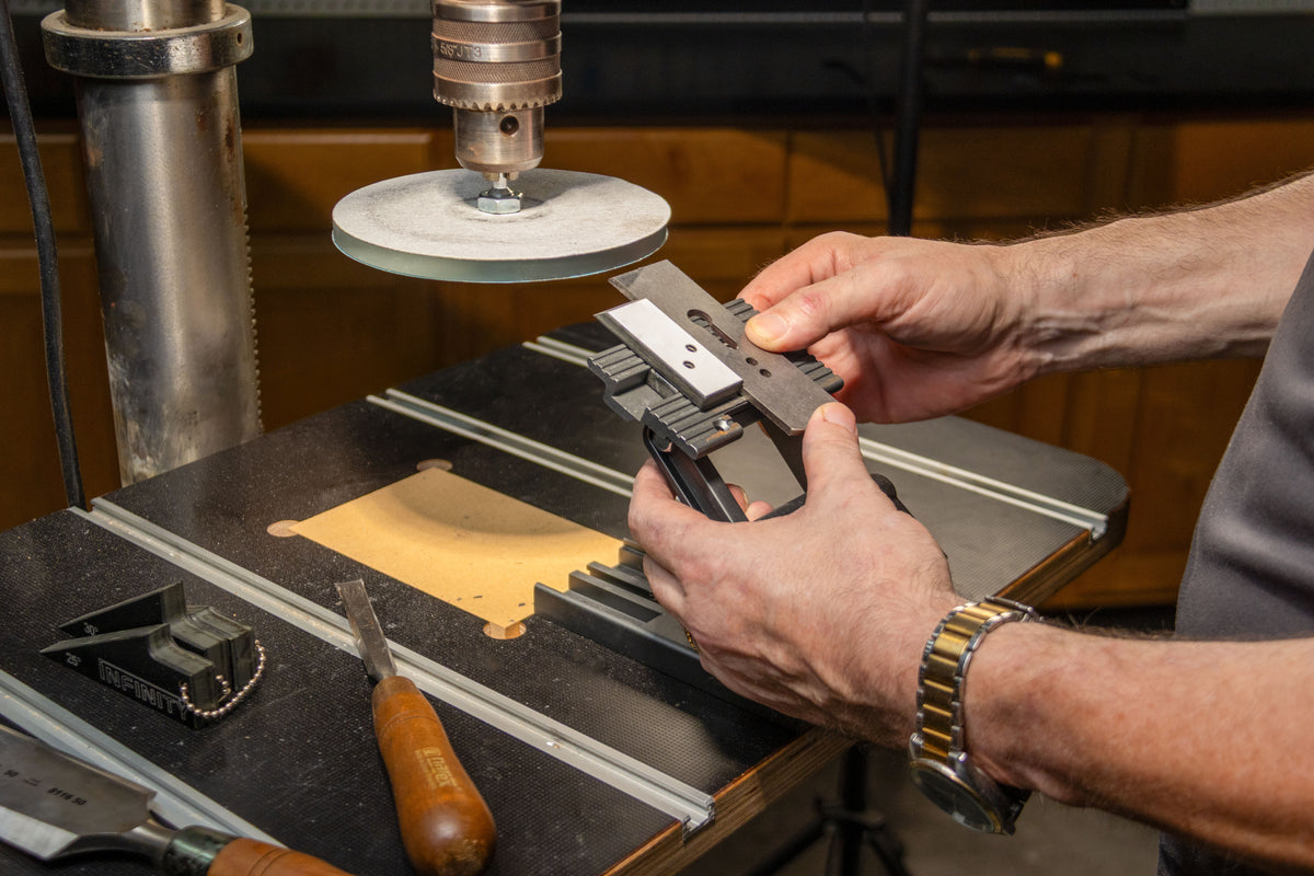 Woodworker sharpening a chisel on the Infinity Tools Drill Press Sharpening Station mounted on a drill press