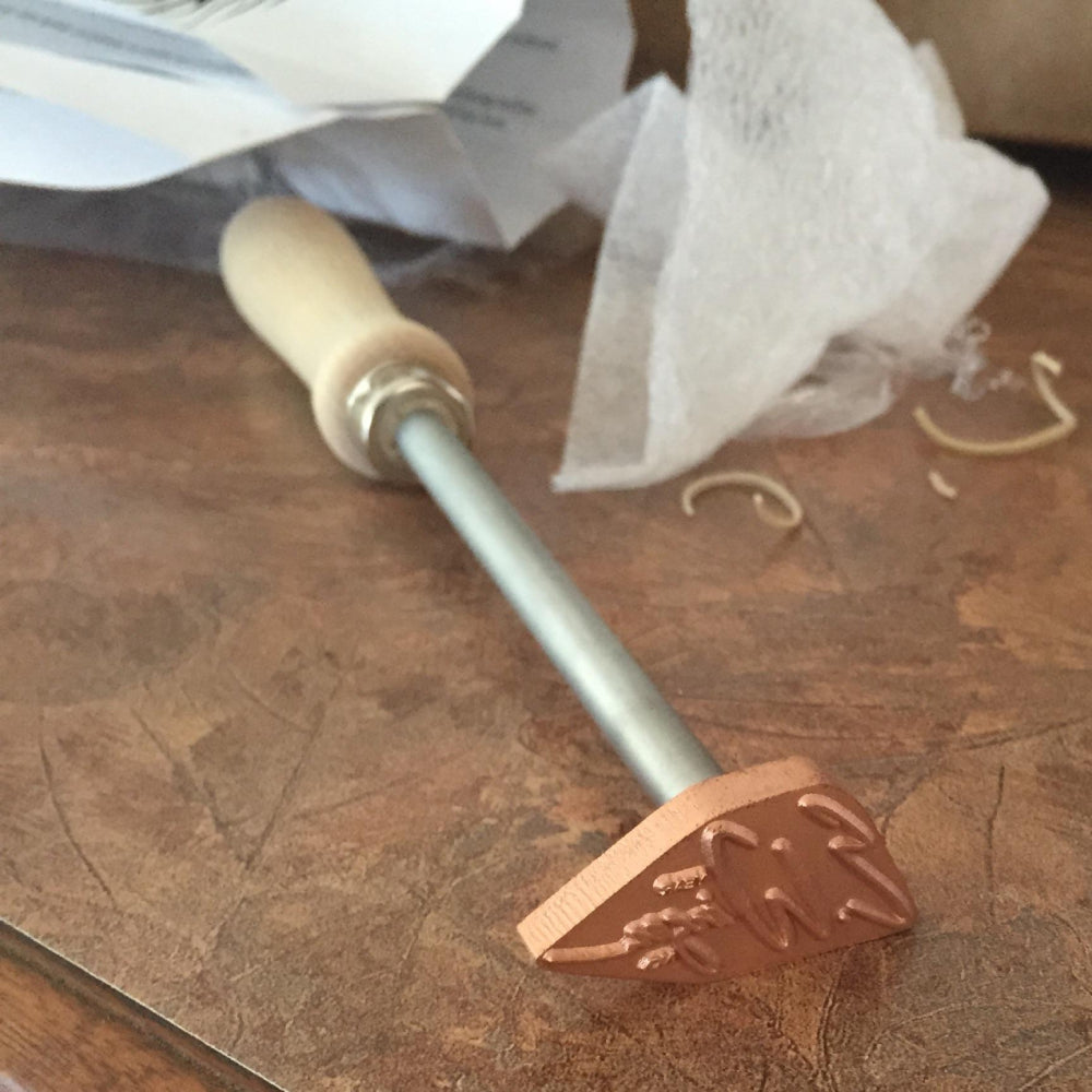 Woodburning branding iron with wooden handle on a workshop table