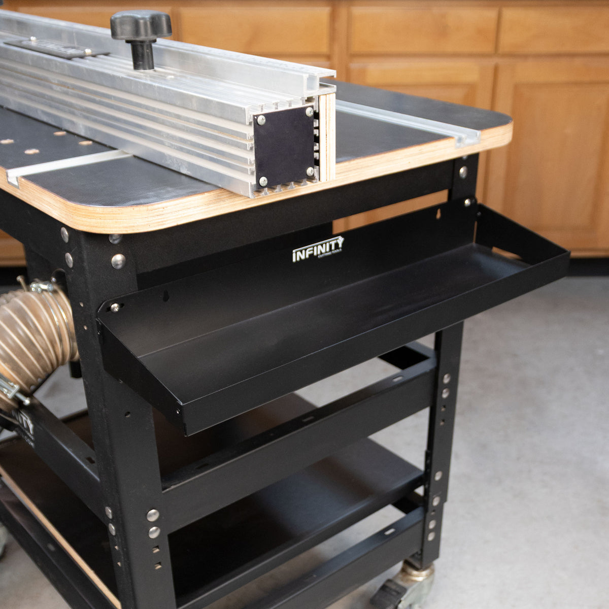 Router table tool tray mounted to a router table sitting on a concrete floor.