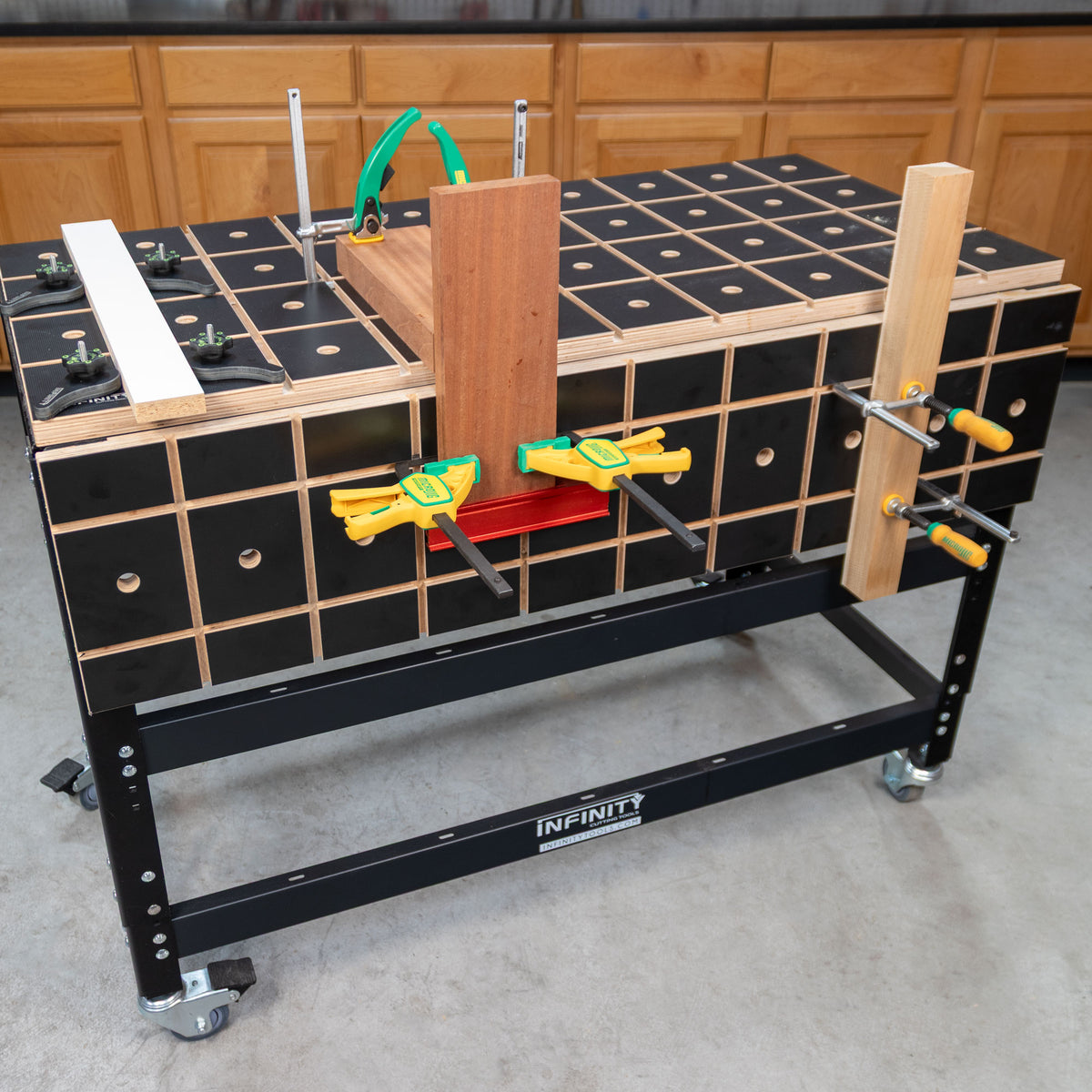 Woodworking workbench with clamping grid, wood pieces, and multiple clamps in workshop