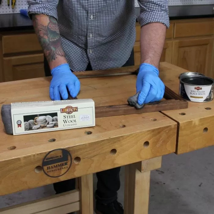 Applying Liberon wax polish to wood with steel wool on a woodworking bench