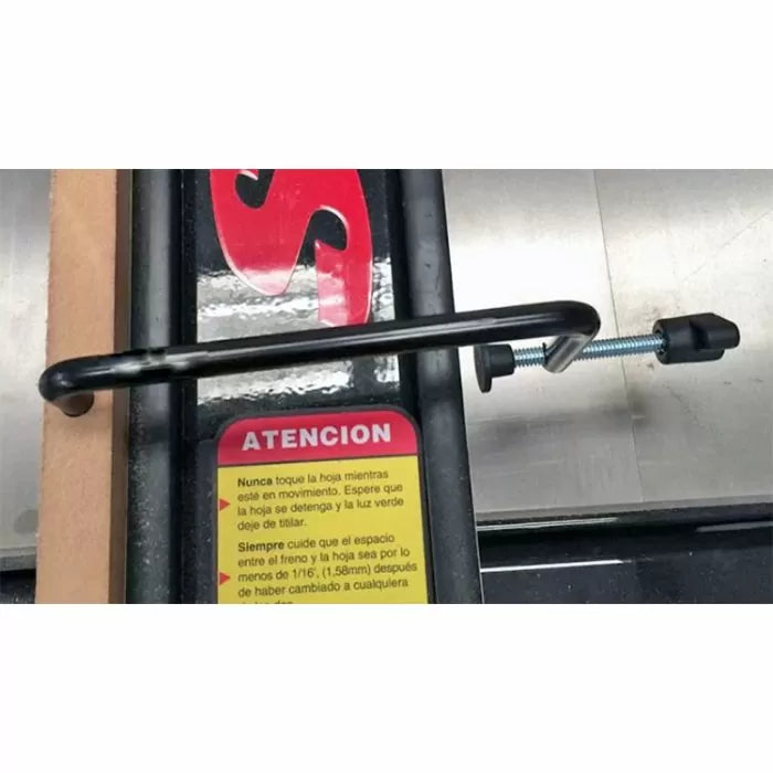 Table saw fence clamp tool securing a wooden workpiece on a metal saw table.
