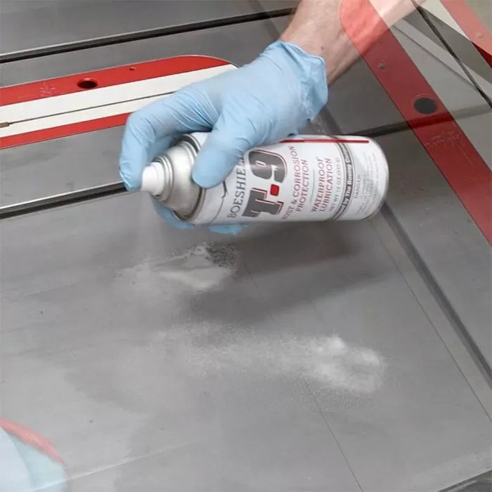 Hand spraying T-9 lubricant on a table saw for corrosion protection and tool maintenance