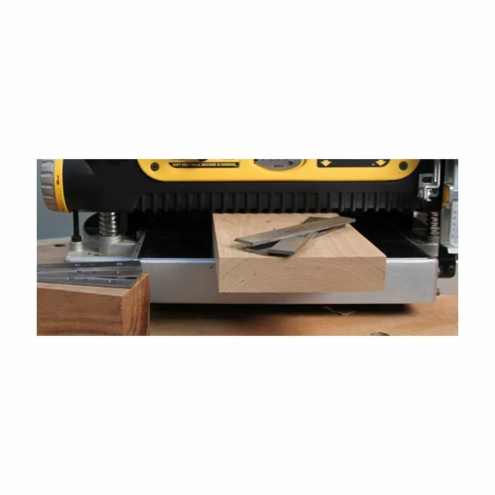 Wood planer with fresh board and planer blades on workbench, woodworking tool in use