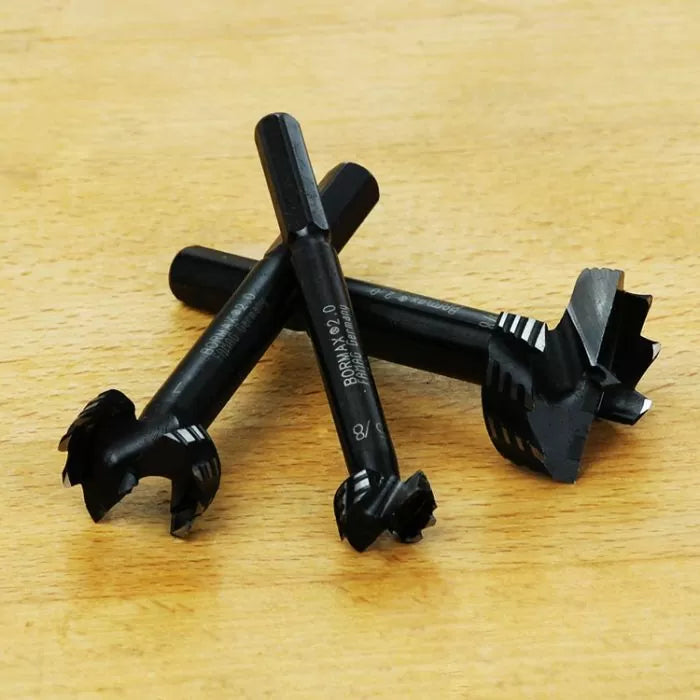 Set of black woodworking Forstner drill bits on a wooden surface