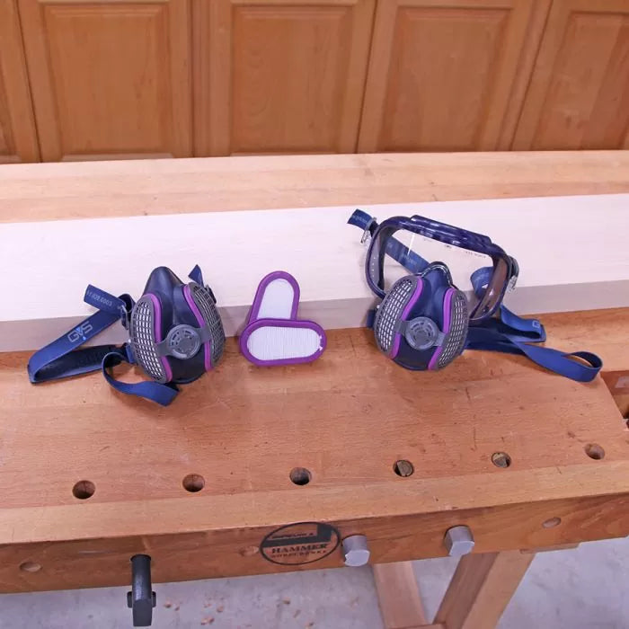 Woodworking respirators, safety goggles, and filters on a workbench in a woodshop.