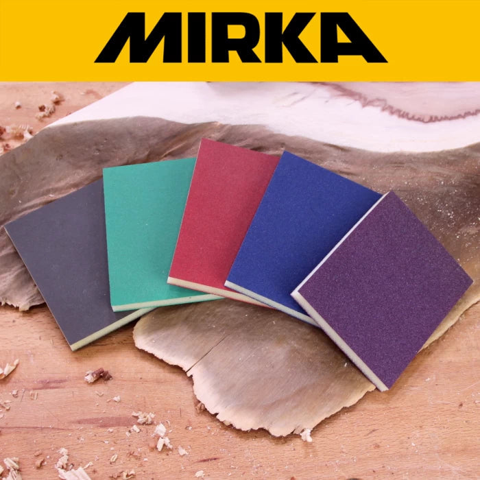 Colorful sanding sponges on a woodworking surface with wood shavings, Mirka logo above.