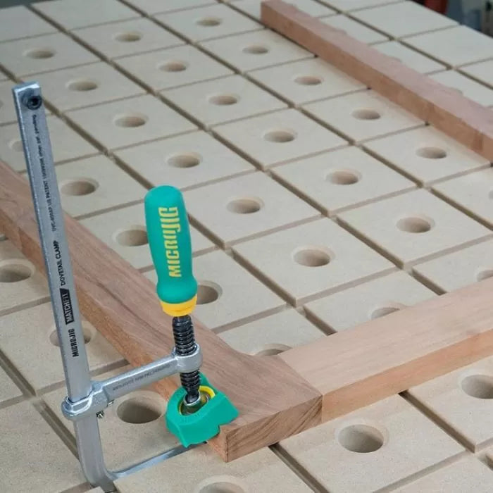 Woodworking clamp securing wood on a hole grid workbench