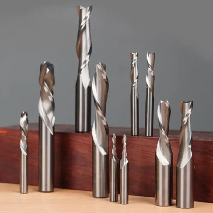 Assorted spiral router bits for woodworking displayed upright on wooden block.