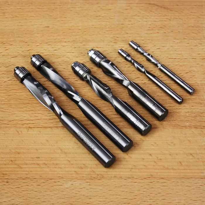 Set of spiral flush trim router bits on a wooden surface, various sizes for woodworking.