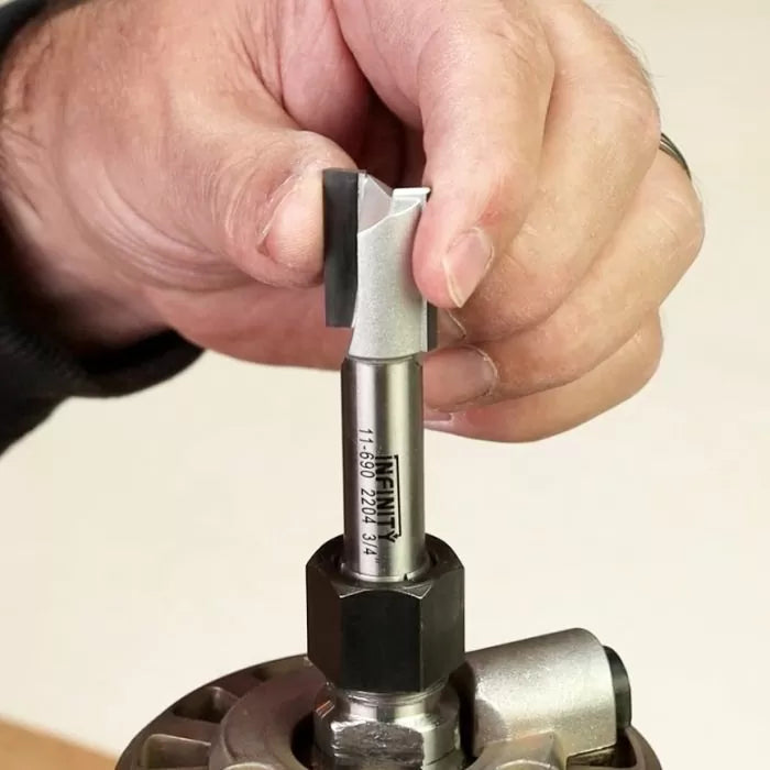 Hand installing a straight router bit into a router collet, woodworking tool closeup.